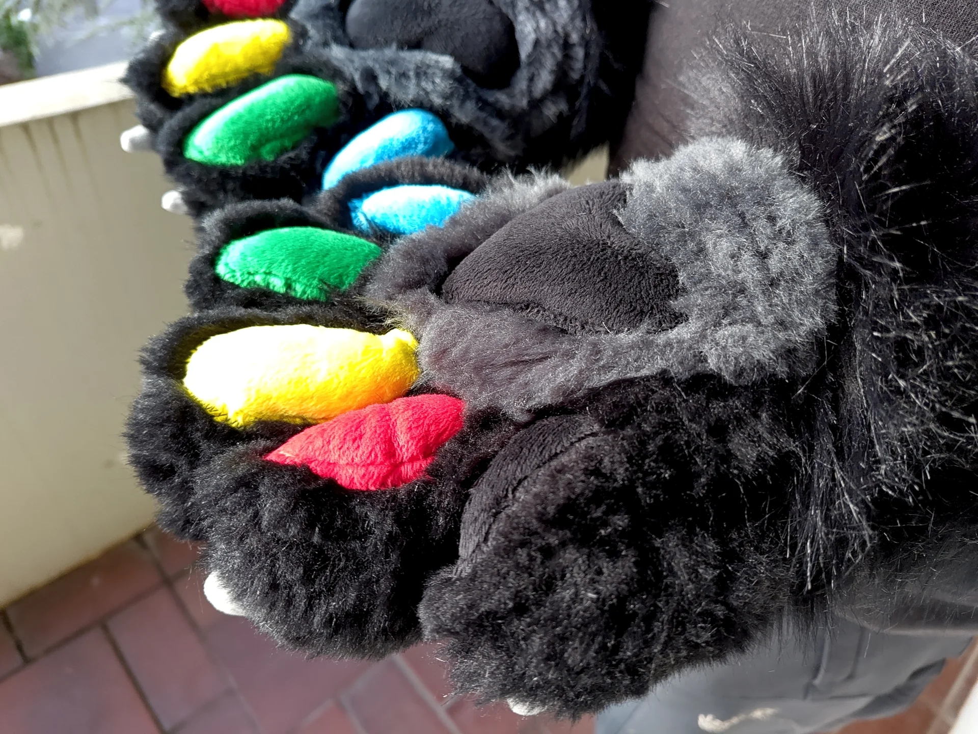 Puffy paws with black faux fur and red, green, blue, yellow and black paw pads.